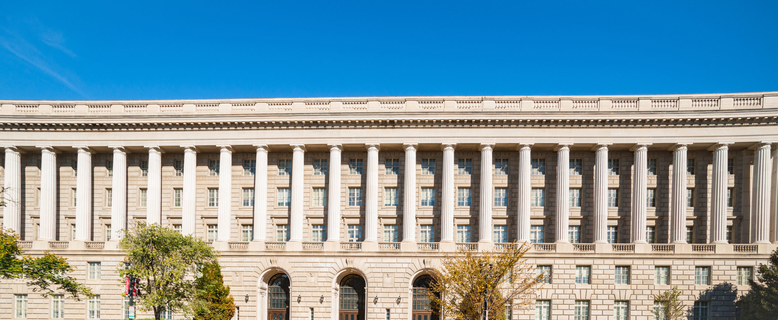 Classical style architecture with repeating design features of columns and windows in banner image.